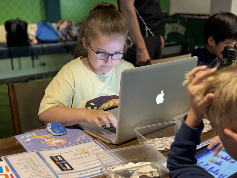 Student focused intently on her laptop during a coding session